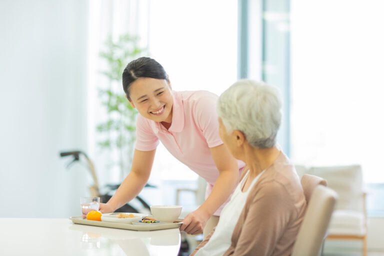 Asian caregiver setting a meal on the table for a care recipient