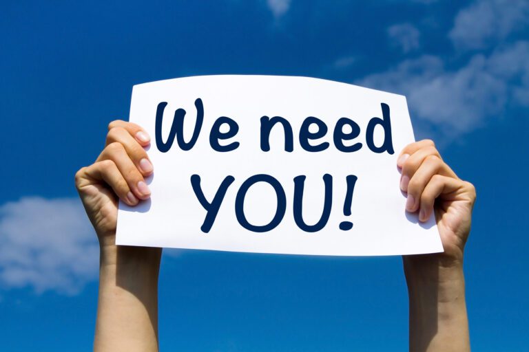hands holding a sign reading we need you to the sky